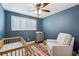 Blue-painted Bedroom featuring a crib, dresser, and comfortable chair, all well lit at 8242 E Briarwood Pl, Centennial, CO 80112