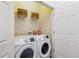 Functional laundry room with modern washer and dryer units and overhead storage shelving at 9471 Ashbury Cir # 202, Parker, CO 80134