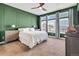 Inviting primary bedroom featuring plush carpet, green accent wall, and bright natural light at 4863 River Landing Ave, Firestone, CO 80504