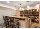 Finished basement bar area featuring stone accent work, seating, and a temperature controlled wine storage area at 3930 S Pinehurst Cir, Denver, CO 80235