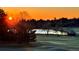 Scenic golf course view featuring a tranquil pond, lush green grass, and a vivid orange sunset at 3930 S Pinehurst Cir, Denver, CO 80235
