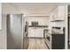 Modern kitchen featuring white cabinets, stainless steel appliances, and stylish flooring at 7770 Kenwood St, Commerce City, CO 80022