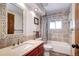 Cozy bathroom with red vanity, decorative mirror, a toilet, and shower with a patterned shower curtain at 10381 Hondah Dr, Littleton, CO 80127
