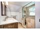 Bathroom featuring a glass-enclosed shower, dual sinks with a marble countertop, and wood tile flooring at 10381 Hondah Dr, Littleton, CO 80127