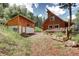 Charming cabin and shed featuring wood siding, complemented by a lush lawn and vibrant flower boxes at 10381 Hondah Dr, Littleton, CO 80127