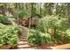 Charming cabin exterior with stairs leading to a small deck, nestled in a serene wooded setting with lush greenery at 10381 Hondah Dr, Littleton, CO 80127