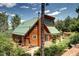 Stunning cabin with a green roof and wood siding nestled among lush trees, showcasing the property's natural beauty at 10381 Hondah Dr, Littleton, CO 80127