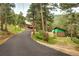 Long driveway leads to home and barn with green roof amid lush foliage and natural beauty at 10381 Hondah Dr, Littleton, CO 80127