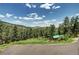 Scenic view of a wooded property featuring a charming cabin, surrounded by lush greenery and rolling hills at 10381 Hondah Dr, Littleton, CO 80127