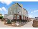 Attractive multi-story townhome featuring brick accents, muted green siding, and a black metal railing at 14283 Currant St, Broomfield, CO 80020