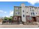 Attractive multi-story townhome featuring brick accents, muted green siding, and a black metal railing at 14283 Currant St, Broomfield, CO 80020