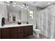 Modern bathroom featuring double vanity with wood cabinets and shower with patterned curtain at 3425 W Moncrieff Pl, Denver, CO 80211