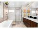 Bright bathroom featuring double vanity, modern fixtures, soaking tub and glass enclosed shower at 3425 W Moncrieff Pl, Denver, CO 80211