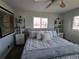 Bright bedroom featuring large bed, ceiling fan, shelving units, and natural light from two windows at 2262 Ammons St, Lakewood, CO 80214