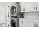 Laundry room with stacked washer and dryer, white cabinets, counter space, and a doorway to another room at 2262 Ammons St, Lakewood, CO 80214