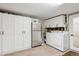 Bright laundry room with washer, dryer, cabinets, and extra refrigerator at 2262 Ammons St, Lakewood, CO 80214