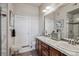 Clean bathroom with double sinks, a marble countertop, a large mirror, and a separate shower, with dark wooden cabinets at 10111 Inverness Main St # 230, Englewood, CO 80112