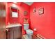 Bathroom featuring vanity with sink, toilet, mirror, and bright red walls at 6527 S Yarrow Way, Littleton, CO 80123