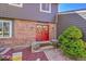 Welcoming home entrance with bright red double doors, brick facade, and lush greenery at 6527 S Yarrow Way, Littleton, CO 80123
