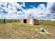 Exterior view of a shed set on a grassy lot with wire fencing at 73 N Dutch Valley Rd, Bennett, CO 80102