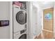 Hallway laundry area featuring a stacked washer and dryer with wood paneled wall in the background at 2235 Edgewood Dr, Boulder, CO 80304
