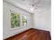 Bedroom with wood flooring, a ceiling fan, and two windows overlooking a tree-lined street at 3870 S Ouray Way, Aurora, CO 80013