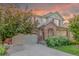 Charming two-story home featuring a brick archway, lush landscaping, and attached two-car garage at 129 N Irvington St, Aurora, CO 80018