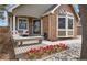 Charming covered front porch with decorative brick, bench seating, and red tulips at 16750 E Prentice Ave, Centennial, CO 80015