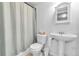 Bright bathroom featuring a pedestal sink, white toilet, and bathtub with a white and grey shower curtain at 154 Falcon Cir, Mead, CO 80542