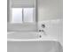 Close up of a white bathtub with white tiled walls and a window at 154 Falcon Cir, Mead, CO 80542