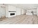 Open concept living room with hardwood floors, modern fireplace, and access to the kitchen with white cabinets at 9742 Cathay St, Commerce City, CO 80022
