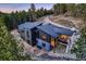 Modern home nestled among mature trees with a stone patio and view of the winding driveway at 21429 Trappers Trl, Morrison, CO 80465