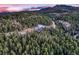 Breathtaking aerial view of a home nestled within a dense forest with mountains in the distance at 21429 Trappers Trl, Morrison, CO 80465