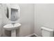 Well-lit bathroom with a pedestal sink, oval mirror, and modern toilet at 1368 Orchard St, Brighton, CO 80601