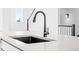 Close up of modern kitchen sink with black faucet and white countertop, with staircase in background at 2672 W 68Th Ave, Denver, CO 80221