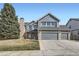 Charming two-story home with a three-car garage and brick and blue siding and large tree at 6493 W 98Th Ct, Westminster, CO 80021