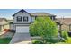 Home exterior with a two-car garage, manicured lawn, and mature shade tree at 12400 Village Cir, Brighton, CO 80603