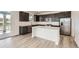 Modern kitchen featuring stainless steel appliances, an island, dark wood cabinets, and light countertops at 627 Nightsky St, Erie, CO 80516
