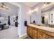 Bathroom with double sink vanity and an open doorway leading into the bedroom at 7440 W 94Th Pl, Westminster, CO 80021