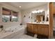 Serene bathroom with a soaking tub, double vanity, and a window with scenic views at 29266 S Sunset Trl, Conifer, CO 80433