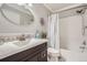 Inviting bathroom featuring a shower-tub combo with stylish shower curtain and a decorative oval mirror at 4495 Windmill Dr, Brighton, CO 80601