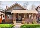 Charming brick home with a welcoming covered front porch with mature landscaping at 910 Steele St, Denver, CO 80206