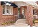 Charming brick home with an inviting covered front porch and beautiful landscaping at 910 Steele St, Denver, CO 80206