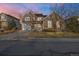Charming two-story home with a stone facade and gray siding, set against a colorful sky at dusk at 13694 Cherry St, Thornton, CO 80602