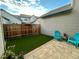 Backyard featuring a small green turf area, brick paver patio, wooden fence, and blue Adirondack chairs at 10087 E Hawaii Pl, Aurora, CO 80247