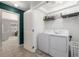 Bright laundry room featuring a washer and dryer, overhead shelving, and a glimpse into another room at 9758 Laredo St # 37C, Commerce City, CO 80022
