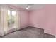 Bright bedroom painted pink with plush carpeting, illuminated by natural light from a large window at 2212 S Naples Way, Aurora, CO 80013