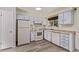Well-lit kitchen with white appliances, light blue cabinetry, and plank flooring at 2212 S Naples Way, Aurora, CO 80013