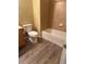 A bathroom with a toilet, a bathtub and shower, and wood-grain vinyl flooring at 9569 Pearl Cir # 204, Parker, CO 80134