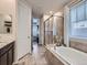 Clean bathroom features a glass enclosed shower, soaking tub, and a double vanity with granite countertops at 18280 W 85Th Dr, Arvada, CO 80007